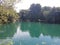 A marine green body of water at rest at the bottom of the great krka waterfalls.