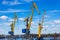 Marine loading cranes of yellow color on a background of blue sky with clouds.