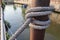 Marine ropes for towing ship bound around pipe steel post in the canal closeup.