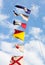 Marine signal flags on a mast against of cloudy sky.