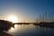 Marine yacht club at sunset in Alghero, Sardinia, Italy. Luxury yachts docked in seaport under colourful sundown. Warm orange