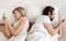 Marital crisis, indifference. Caucasian couple using cellphones, lying back-to-back in bed, above view