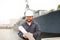 Maritime engineer looking at blueprints and standing near vessel.