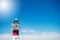 Maritime lighthouse on cliff with blue sky in the background