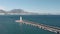 Maritime lighthouse in sea with walking path. People walk to lighthouse of Alanya, Turkey. Aerial drone shot of sea harbor with ci