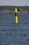 A maritime navigational buoy floating on the calm water. Skerries in the background