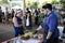 A market chef talks with a woman during a cooking demonstration.