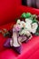 Maroon Colored High Heels on a Red Couch with a White Rose Bouquet