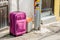 Maroon colored suitcase on street