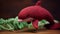 Maroon Knitted Dolphin Toy On Green Table With Plants