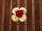 A maroon rose blooms on top of cream muffins on a wooden countertop on a Sunny summer day. Confectionery on display.