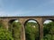 Marple viaduct stand in the vally , behind a little cottage