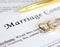 Marriage contract with two golden wedding rings and gold pen, prenuptial agreement, macro close up, sign with signanture