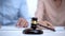 Marriage rings and gavel closeup, spouses signing divorce document on background