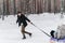 A married couple is having fun in the forest at the weekend. A man rides a woman on a tubing in the snow in a winter