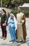 A married couple - husband and pregnant wife in the clothes of Jesus` time sing a song before entering the Basilica of the Annunci