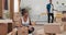 Married couple moves into new apartment woman sits on floor unpacking cardboard boxes of stuff unrolls items from paper