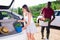 Married couple puts basket and bucket of vegetables in the trunk of car