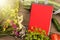 marrow squash, measure tape, blank red notepad, flowers, tomatoes and cucumbers on brown wooden table