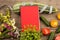 marrow squash, measure tape, blank red notepad, flowers, tomatoes and cucumbers on brown wooden table