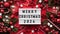 Marry Christmas banner concept.White board with text Happy Xmas 2024 among Christmas red decor,balls,berries, striped candy canes,