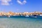 Marsaxlokk historic port with many boats in transparent sea, Malta. Blue sky and village background.