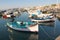 Marsaxlokk, Malta, August 2019. Small Maltese fishing boats at the pier against the backdrop of the city.