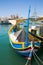 Marsaxlokk, Malta, August 2019. Yellow-blue fishing boat at the pier in the city center.