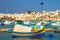 Marsaxlokk market with traditional colorful Luzzu fishing boats, Malta