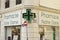 Marseille, France - October 12, 2018: close-up of led green cross, pharmacy symbol, at the corner of Mediterranean architecture