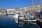 Marseille old town main harbour front with busy crowded fish market, fish monger selling fish nearby their fishing boats