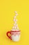 Marshmallows, sugar cubes and candy sticks in a holiday mug on a yellow background