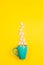 Marshmallows, sugar cubes and candy sticks in a turquoise star mug on a yellow background