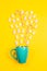 Marshmallows, sugar cubes and candy sticks in a turquoise star mug on a yellow background