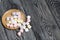 Marshmallows on a wooden plate. A little scattered nearby. On black pine planks