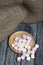 Marshmallows on a wooden plate. A little scattered nearby. On black pine planks