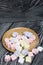 Marshmallows on a wooden plate. A little scattered nearby. On black pine planks