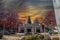 A Marta station with a Christmas tree and red autumn trees and lush green plant with tall light posts and powerful clouds