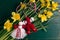 Martenitsa, Martisor on a bouquet of yellow daffodils on a green wooden table top view