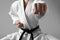 Martial arts master in keikogi with black belt against grey background, focus on fist