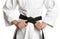 Martial arts master in keikogi with black belt on white background, closeup