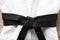 Martial arts uniform with black belt on white wooden background, closeup