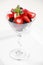 A martini glass full of assorted berries on a white background including strawberries, blackberries, and raspberries