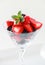 A martini glass full of assorted berries on a white background including strawberries, blackberries, and raspberries