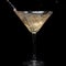 In a martini glass, vermouth ice falls, and splashes with drops on a black background