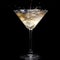 In a martini glass, vermouth ice falls, and splashes with drops on a black background