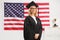 Marture woman wearing a graduate gown and posing in front of USA flag