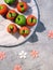 Marzipan sponge apples, green and red. Tasty creative dessert. Flat lay on marble board with wooden flowers on grey.