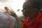 Masai male making fire by rubbing sticks together in village near Tsavo National Park, Kenya, Africa