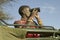 Masai scout with binoculars looks for animals from a Landcruiser during a tourist game drive at the Lewa Wildlife Conservancy in